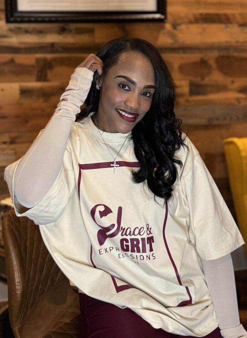 Smiling woman in a white sweatshirt with curly hair poses indoors.