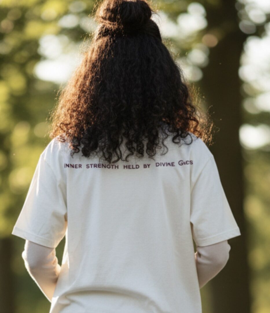 Person with curly hair wearing a white shirt outdoors.