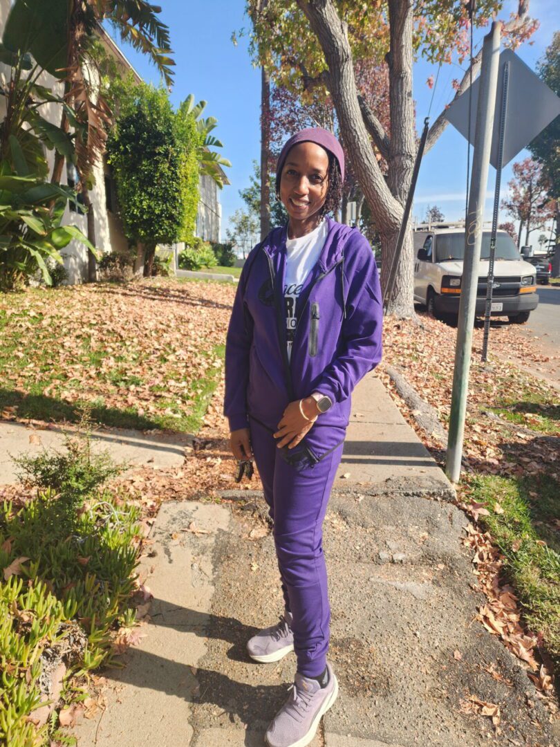 Person standing on sidewalk wearing a purple outfit.