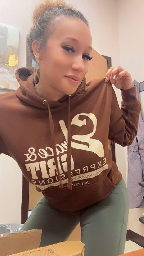 Person wearing a brown hoodie with a white graphic design.