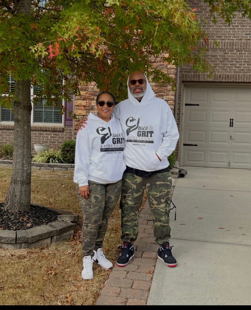 A couple in matching sweatshirts and sunglasses posing outdoors.