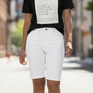 Person wearing white Bermuda shorts and a black graphic T-shirt outdoors.